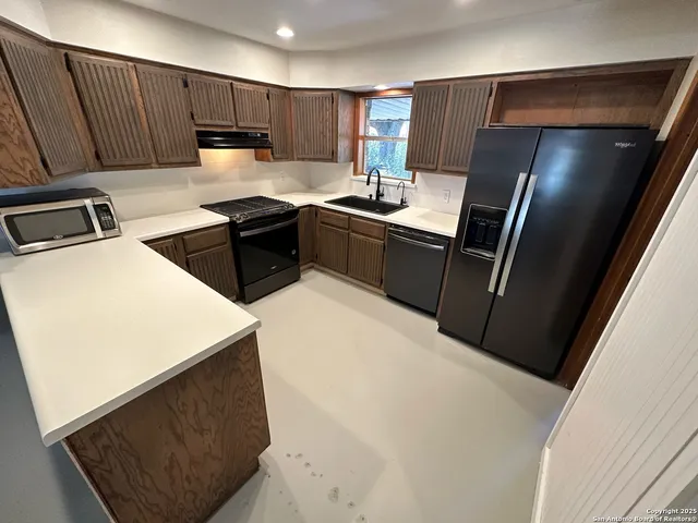 a kitchen with stainless steel appliances a refrigerator a sink a stove a microwave a sink and a refrigerator