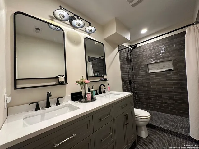 a bathroom with a double vanity sink toilet and mirror