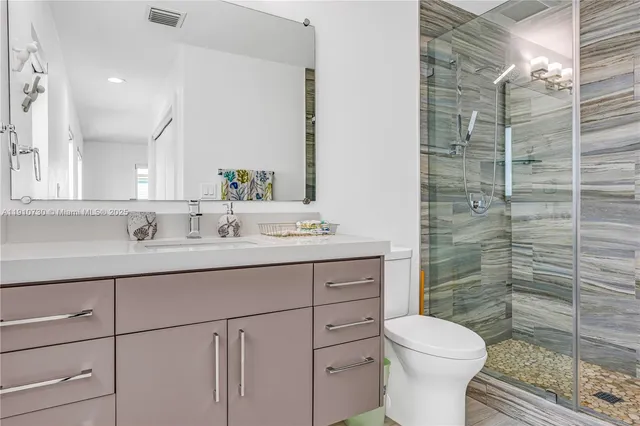 a bathroom with a granite countertop sink toilet and shower