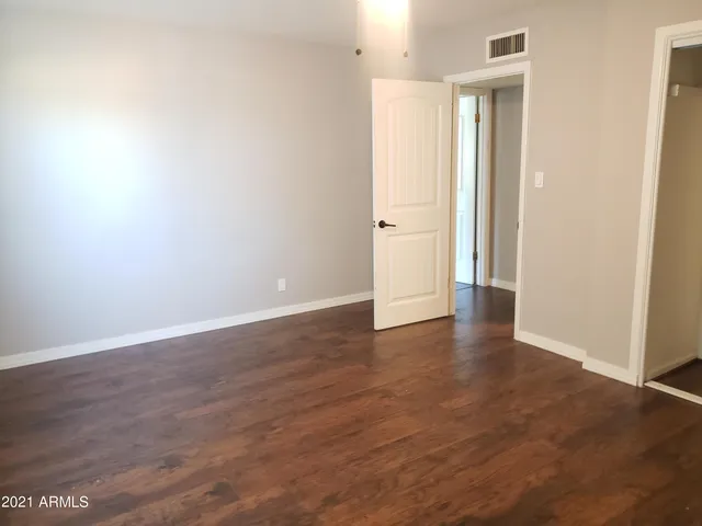 a view of an empty room with wooden floor and closet