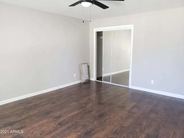 an empty room with wooden floor and ceiling fan