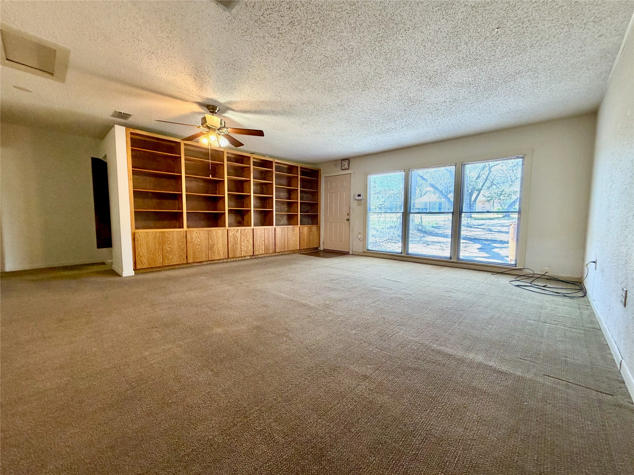 305 West Caddo Street Austin, TX 78753 - Photo 11 of 13 Wall of windows lets natural light in. Storage space behind the wall with built in bookshelves offers an option to expand.
