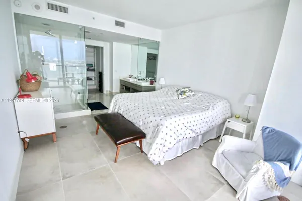 a bedroom with a bed and a walk in closet with wooden floor