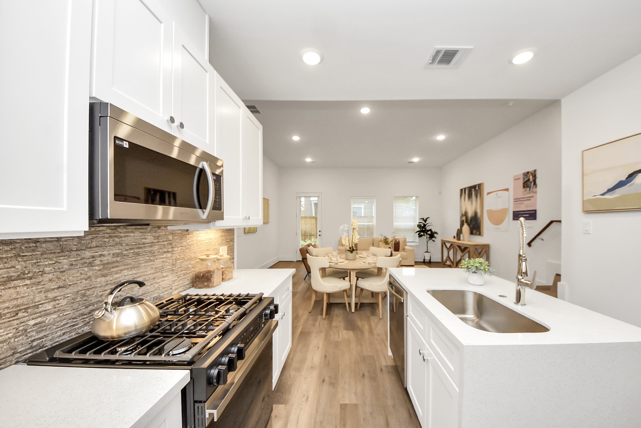 a kitchen with stainless steel appliances a stove a sink a microwave a stove and white cabinets