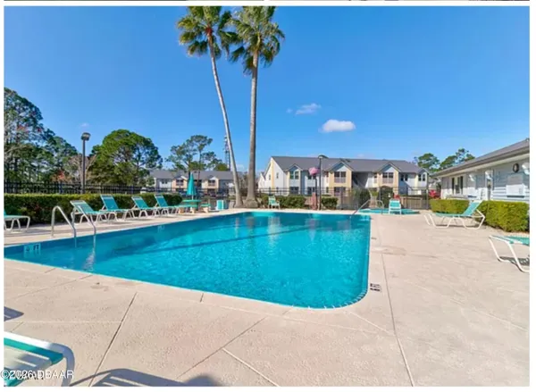 a view of a swimming pool with a yard and palm trees