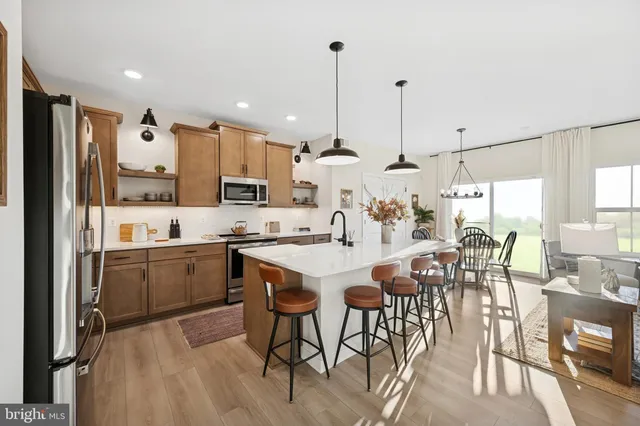 a kitchen with stainless steel appliances kitchen island granite countertop a table chairs and a refrigerator