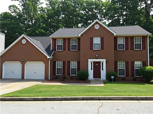 a front view of a house with a garden and trees