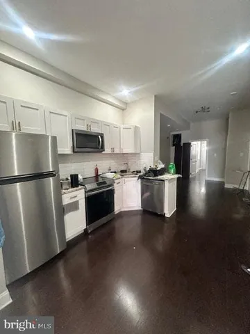 a kitchen with stainless steel appliances a refrigerator a stove a sink dishwasher a oven with white cabinets and wooden floor