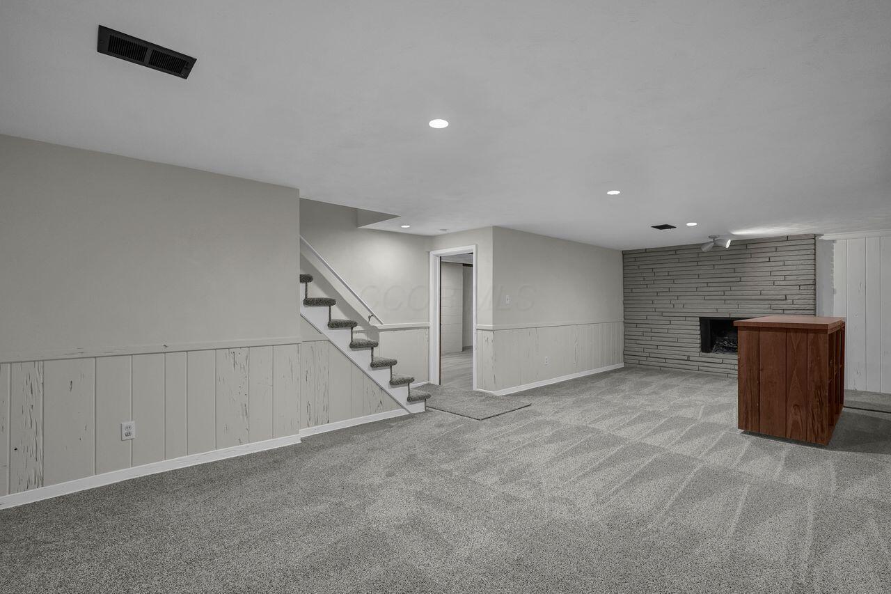 1535 Kenwick Road Columbus, OH 43209 - Photo 18 of 26 Finished basement rec room with new carpet, wainscoting, bar area, and stone fireplace wall.