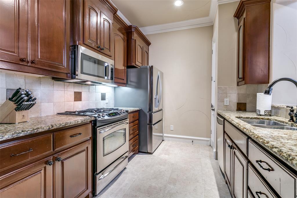 800 Rockingham Drive Irving, TX 75063 - Photo 20 of 35 Kitchen featuring appliances with stainless steel finishes, backsplash, light stone counters, crown molding, and light tile floors