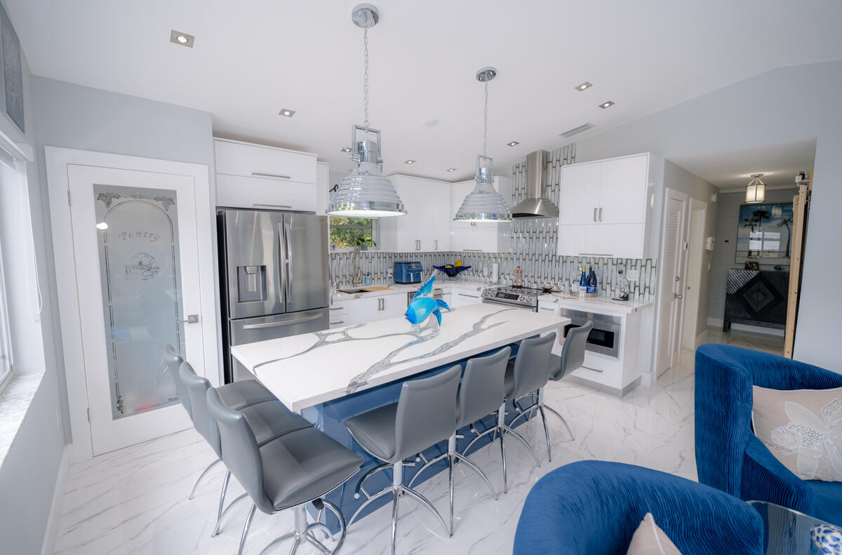 1016 Gibraltar Road Key Largo, FL 33037 - Photo 8 of 49 a view of a dining room and livingroom with furniture wooden floor kitchen view and a chandelier