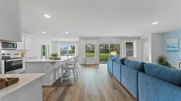 a living room with stainless steel appliances granite countertop furniture wooden floor and kitchen view