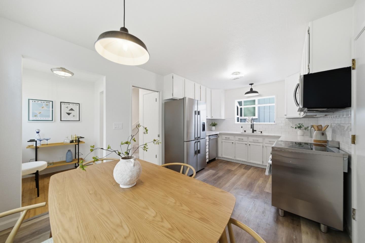 495 Ebken Street Pacifica, CA 94044 - Photo 16 of 52 a kitchen with stainless steel appliances granite countertop a sink dishwasher a stove a refrigerator with a dining table and chairs with wooden floor