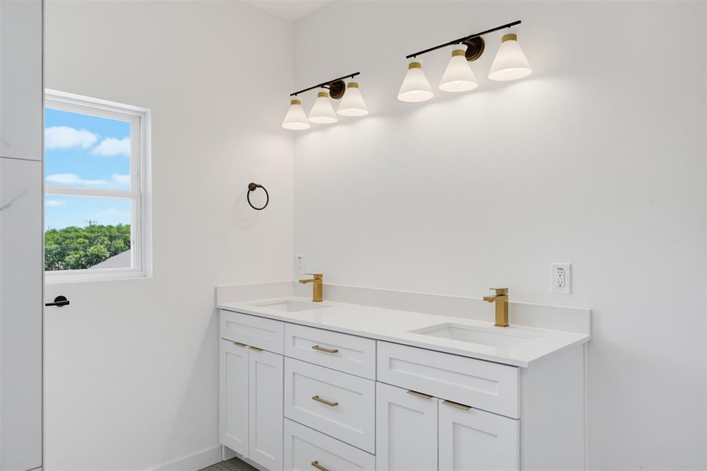 512 South O Connor Road Irving, TX 75060 - Photo 15 of 21 Double vanity with white cabinetry, gold-finish hardware, and a light-toned countertop
