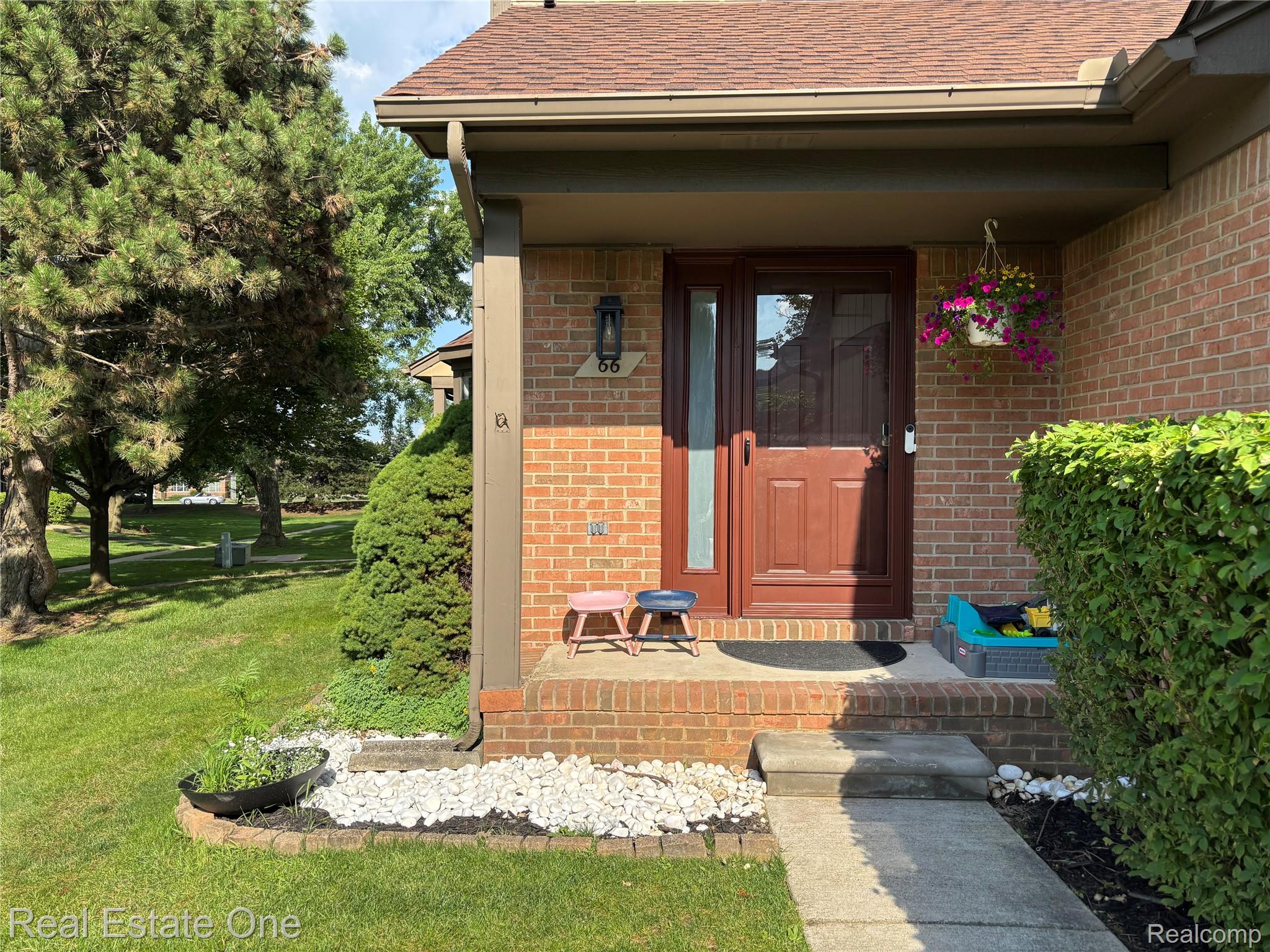 66 Meadow Wood Drive Rochester, MI 48307 - Photo 2 of 20 Brick exterior with a covered entryway, featuring a brown paneled door with an integrated screen