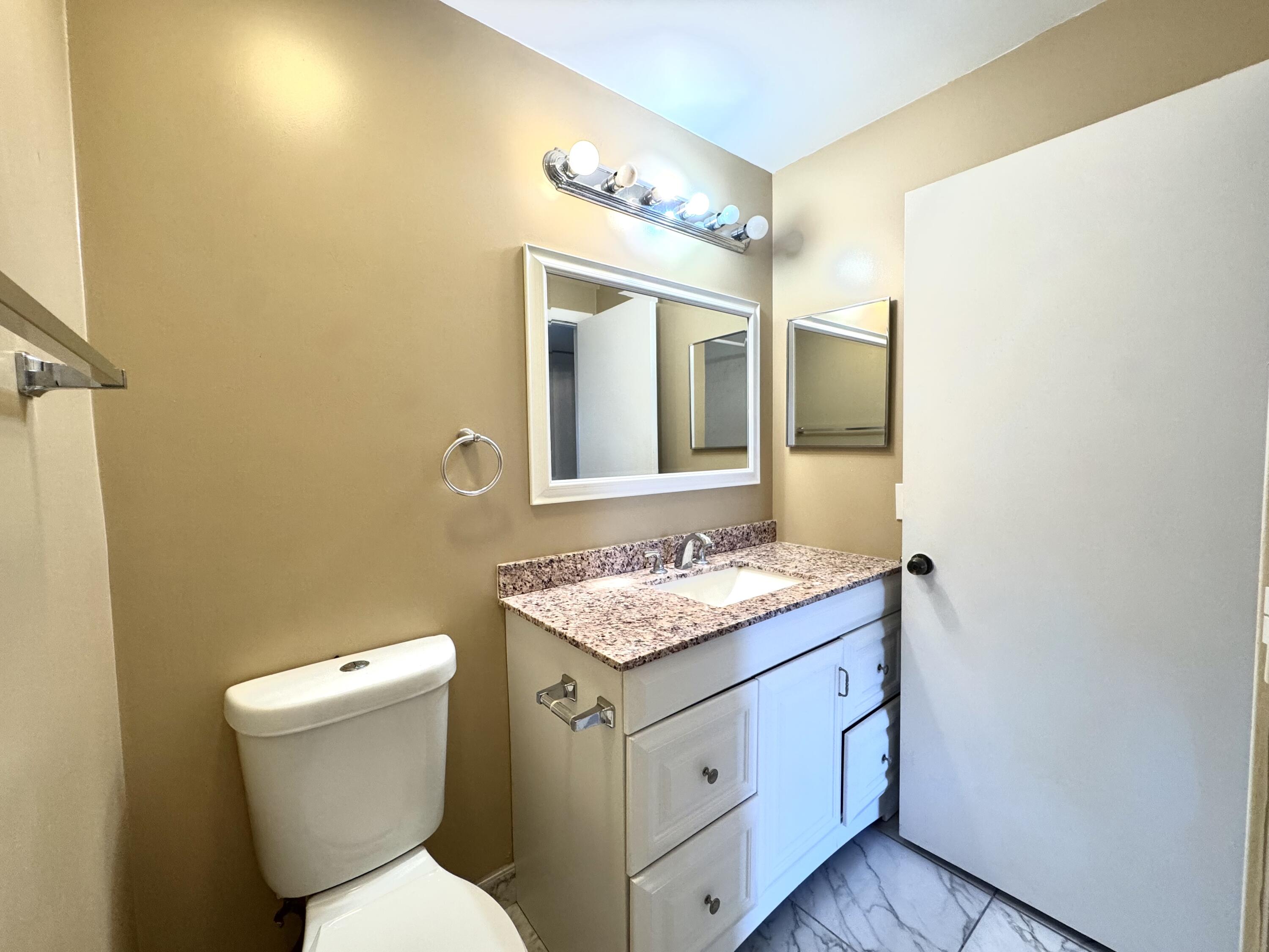 900 Normandy Lane Delray Beach, FL 33484 - Photo 17 of 22 a bathroom with a granite countertop toilet sink and mirror