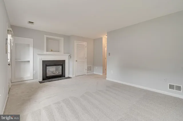 a view of an empty room with a fireplace and a window