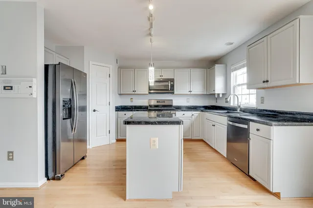 a kitchen with granite countertop white cabinets and stainless steel appliances