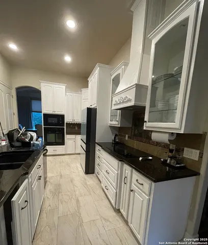 a kitchen with granite countertop a sink and a stove top oven