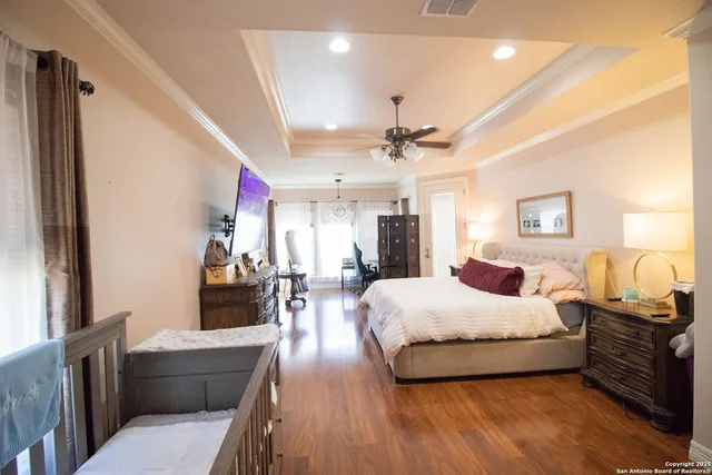 a spacious bedroom with a bed a dresser and wooden floor