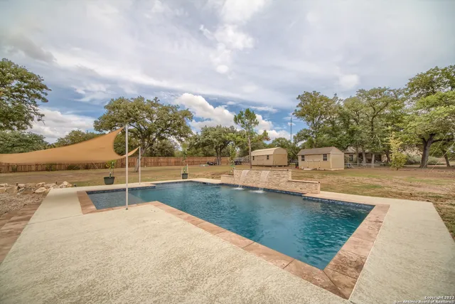 a view of swimming pool with outdoor seating and trees in the background