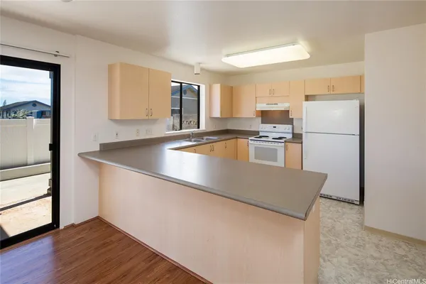 a kitchen with stainless steel appliances granite countertop a refrigerator a stove and a sink with wooden floor
