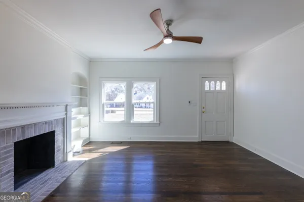 an empty room with windows fireplace and wooden floor