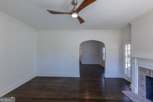 an empty room with wooden floor fireplace and windows