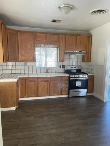 a large kitchen with granite countertop a stove a sink a refrigerator and cabinets