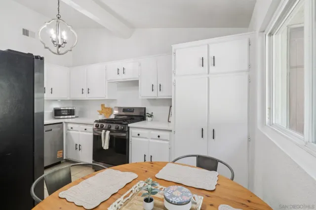 a kitchen with stainless steel appliances a stove a sink dishwasher and white cabinets with wooden floor