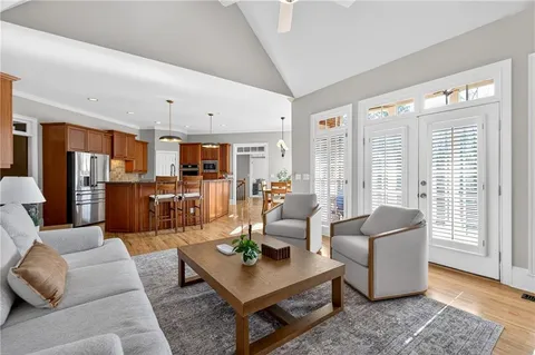 a open kitchen with stainless steel appliances granite countertop a refrigerator a sink dishwasher a dining table and chairs with wooden floor