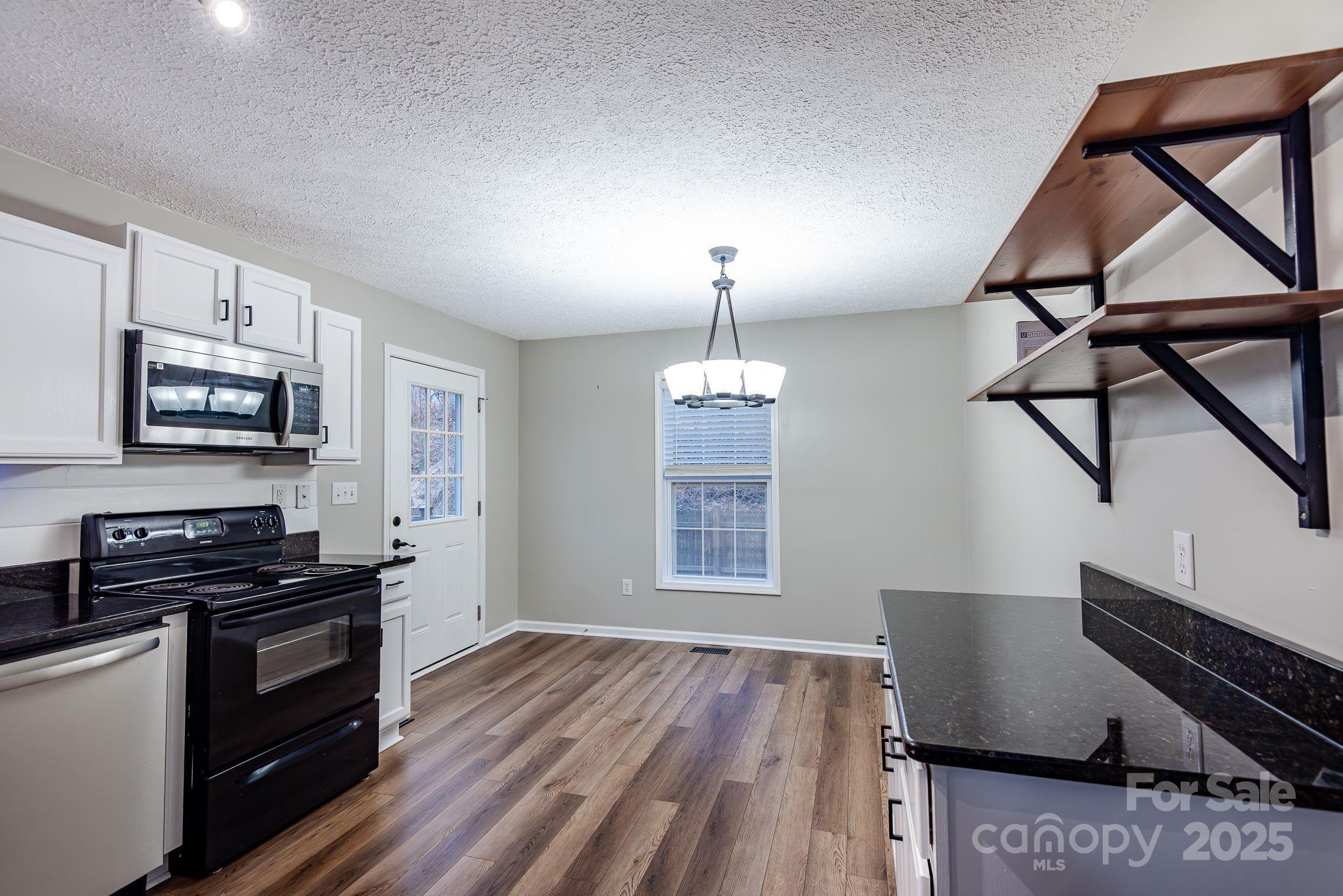 263 Newberry Drive Fletcher, NC 28732 - Photo 21 of 29 a kitchen with stainless steel appliances granite countertop a stove a sink dishwasher and a microwave with wooden floor