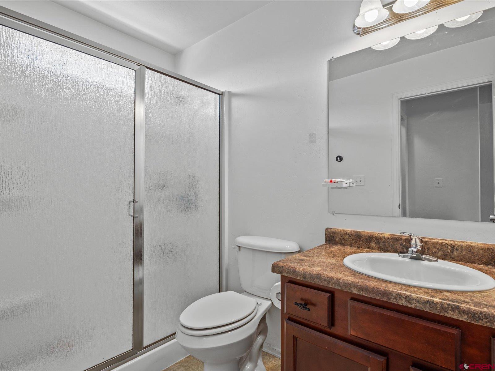 2473 Brookwillow Loop Grand Junction, CO 81505 - Photo 10 of 19 a bathroom with a granite countertop sink toilet a mirror and shower
