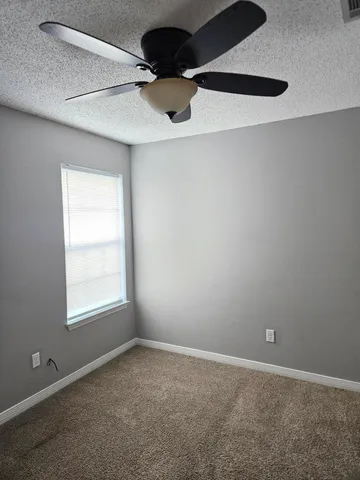 an empty room with a ceiling fan and window