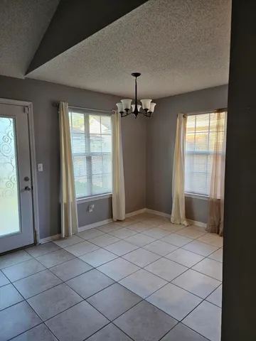 an empty room with chandelier and windows