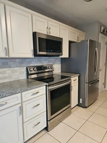 a kitchen with white cabinets stainless steel appliances and a counter top space