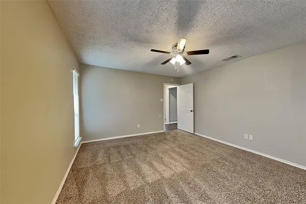 an empty room with ceiling fan and window
