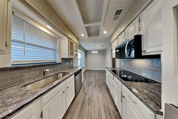 a kitchen with stainless steel appliances granite countertop a sink a stove and cabinets