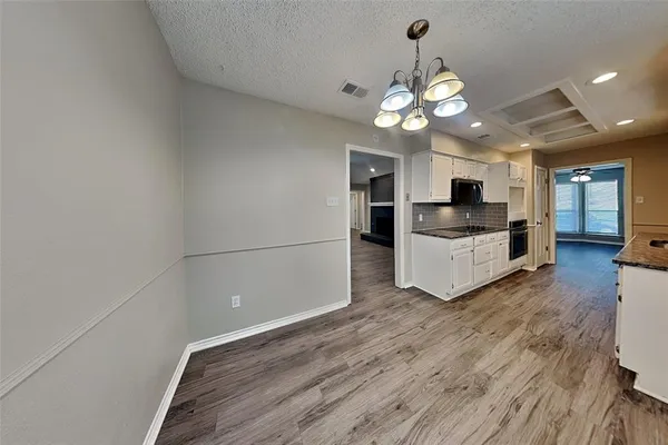 a view of a hallway with wooden floor and a kitchen