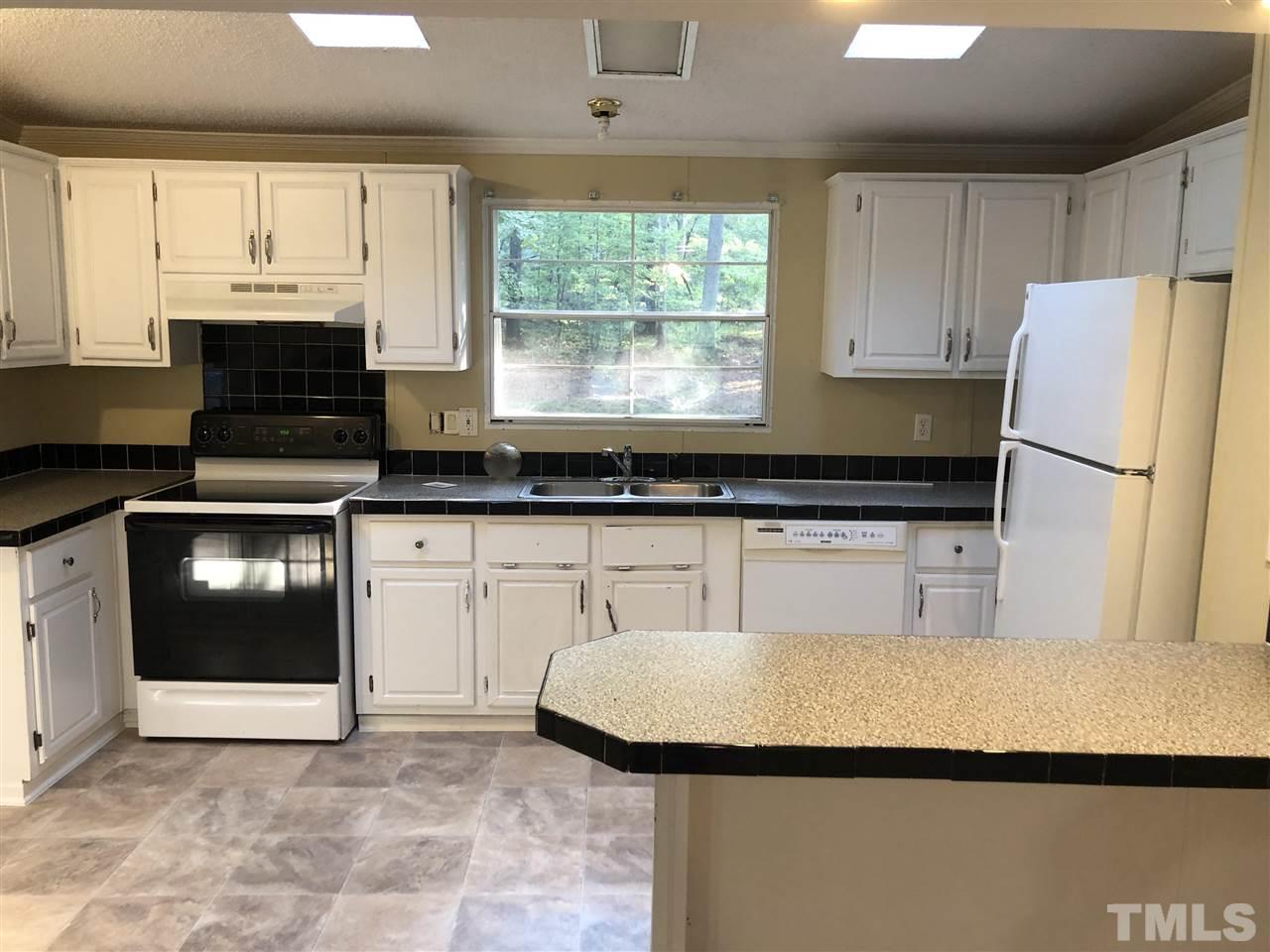 1320 Yakimas Road Raleigh, NC 27603 - Photo 3 of 14 a kitchen with kitchen island granite countertop a sink a stove a refrigerator and cabinets