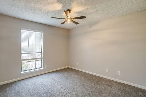 an empty room with windows and fan