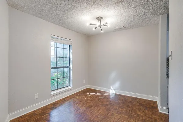 an empty room with chandelier fan and windows