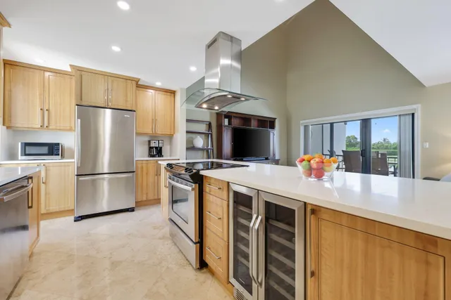 a kitchen with stainless steel appliances a stove a refrigerator a sink a oven with white cabinets and wooden floor