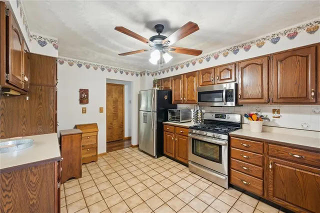 a kitchen with stainless steel appliances granite countertop a refrigerator a sink dishwasher a stove and white cabinets with wooden floor