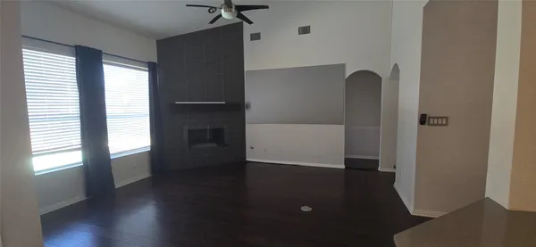 an empty room with wooden floor cabinet and windows