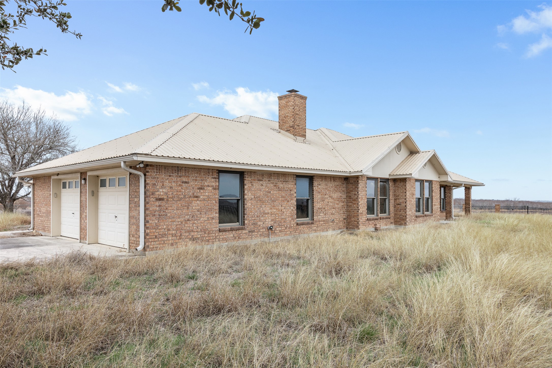 0 Political Road Lockhart, TX 78644 - Photo 8 of 31 Rear view of property with brick siding, a garage, a chimney, and a metal roof