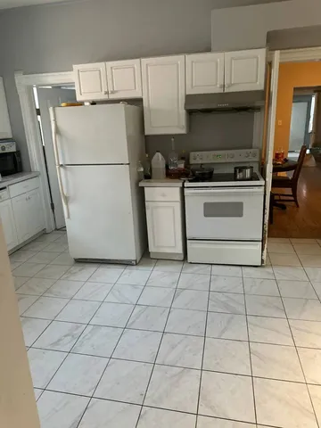 a white refrigerator freezer and a stove sitting inside of a kitchen