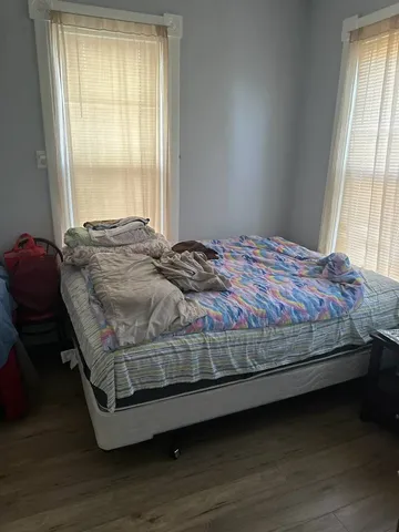 a bedroom with a bed wooden floor and a large window