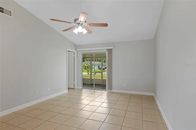 a view of an empty room with window and chandelier fan