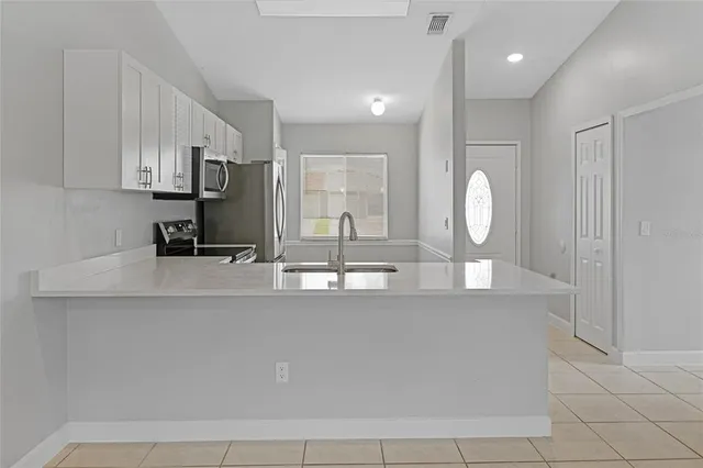 a view of a kitchen with kitchen island a sink stainless steel appliances and cabinets